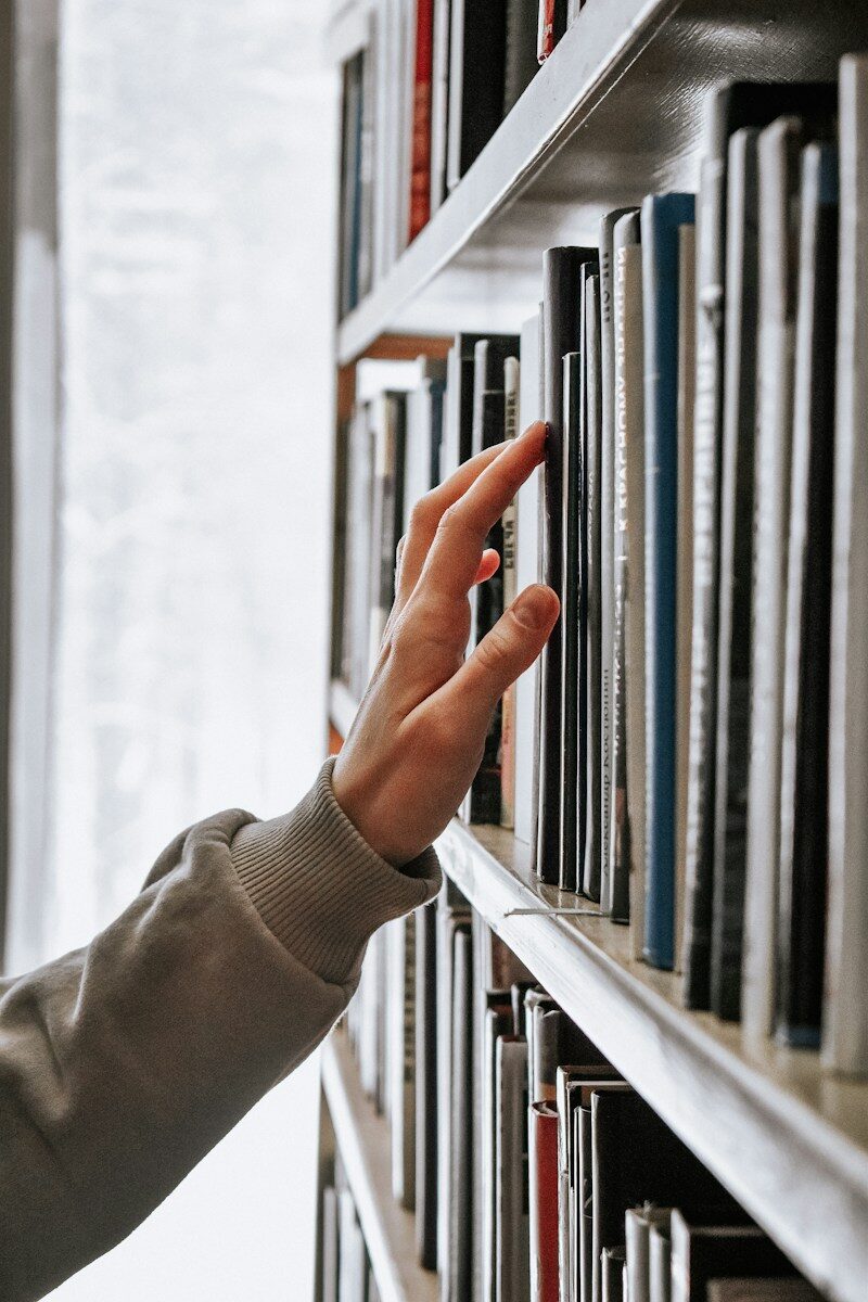 hand reaching for books on shelf