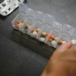 person about to pick medicine from medicine organizer