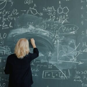 Woman writing complex mathematical formulas on a chalkboard