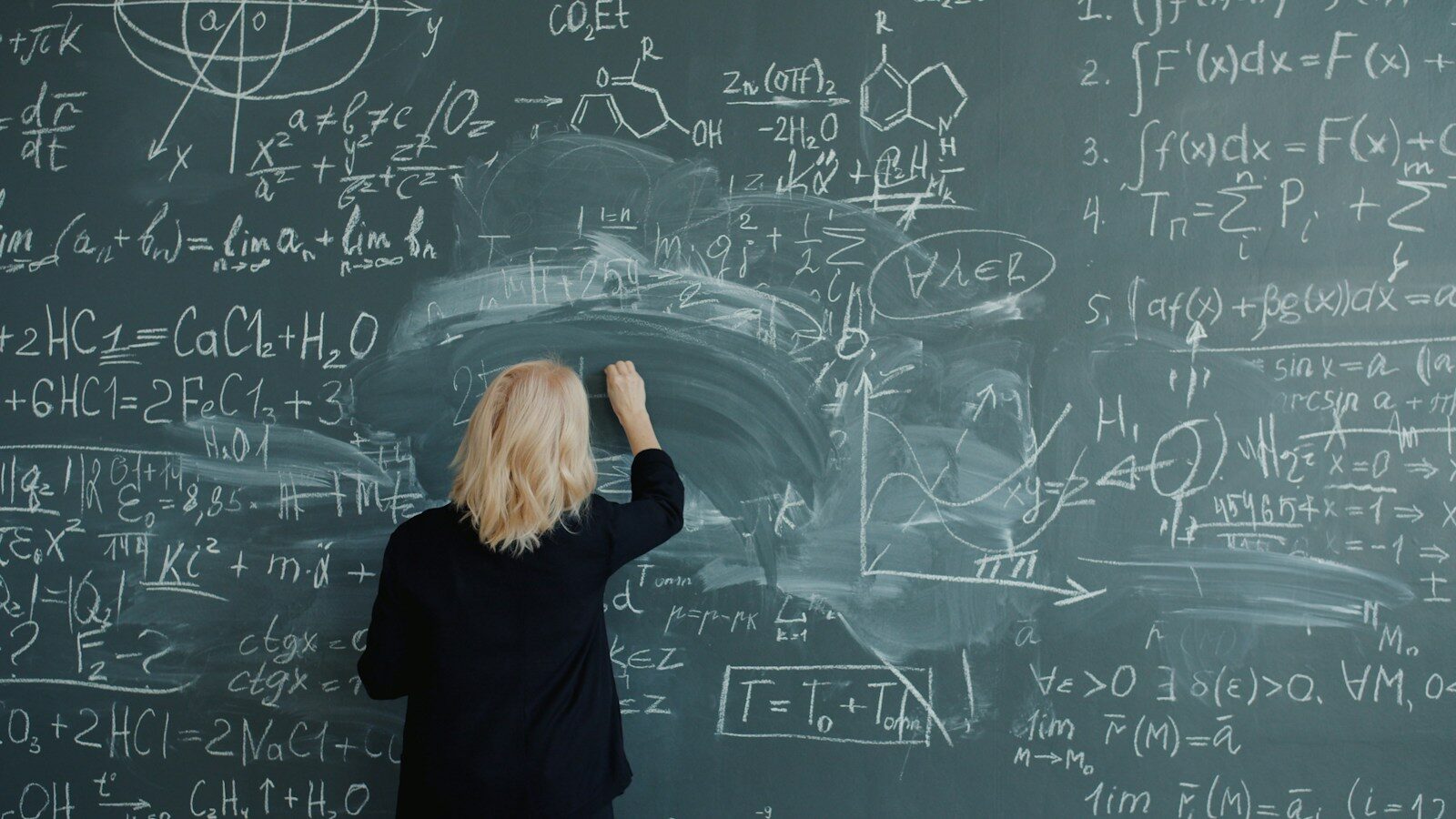 Woman writing complex mathematical formulas on a chalkboard