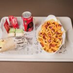 Burrito, cheese fries, and soda on a tray