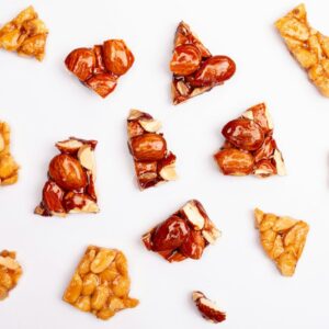 Assortment of peanut brittle pieces scattered on white background