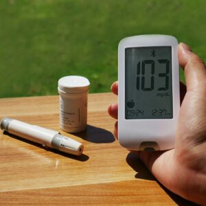 a person holding a blood glucose meter next to a bottle of test strips