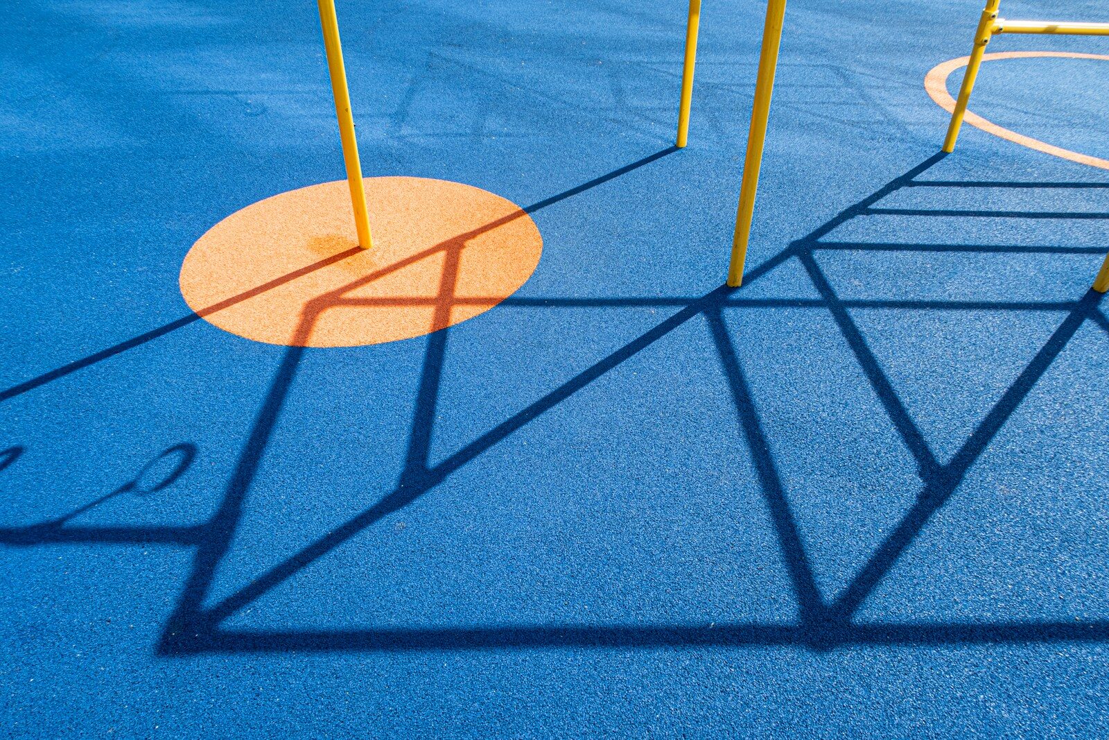 A playground with a blue ground and yellow poles