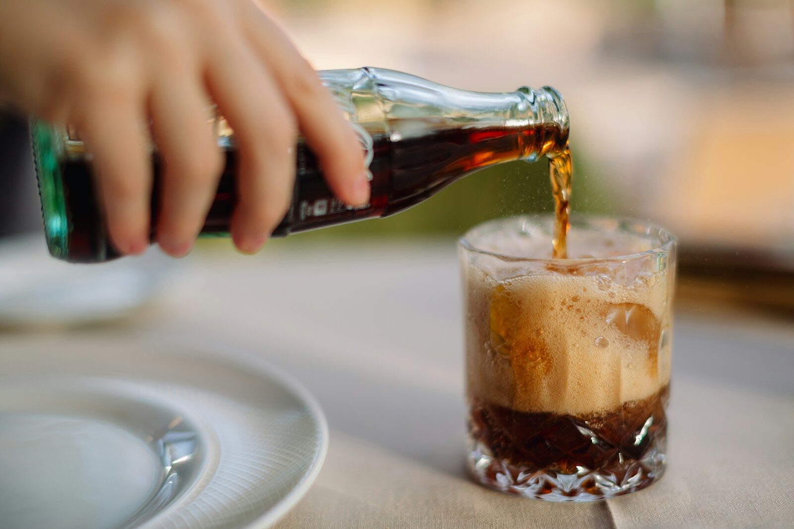 a person pouring a soda into a glass