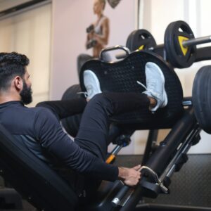 man in black long sleeve shirt sitting on a leg press exercise machine